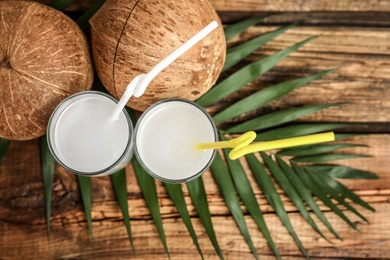 Photo of Flat lay composition with glasses of coconut water on wooden background