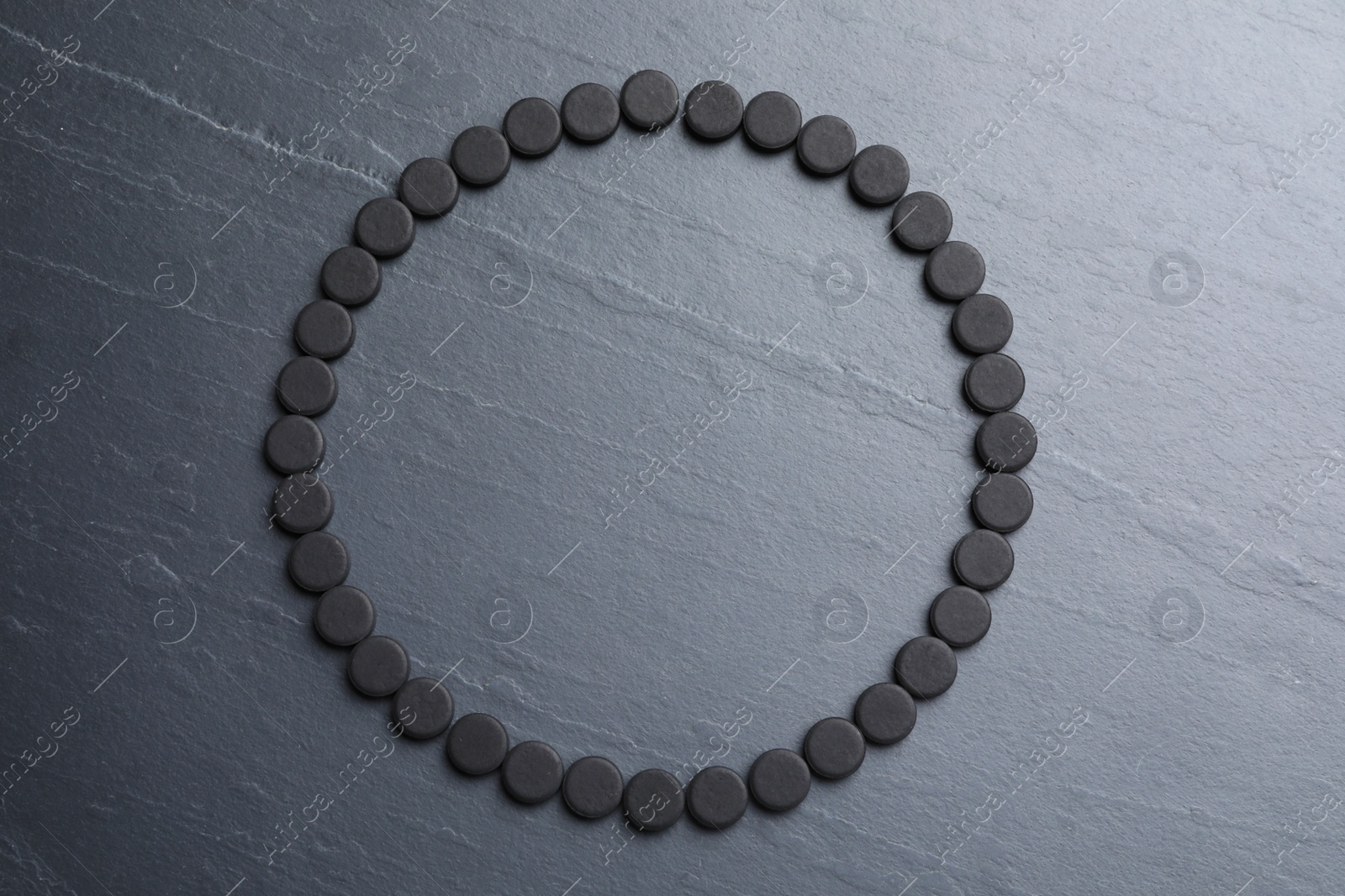 Photo of Frame of activated charcoal pills on black table, flat lay with space for text. Potent sorbent