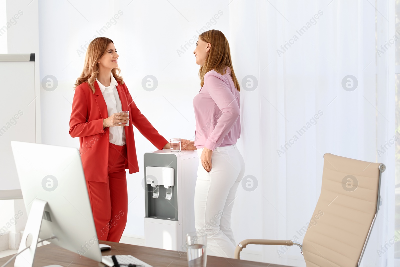 Photo of Women having break near water cooler at workplace