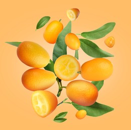 Image of Delicious fresh kumquats and green leaves falling on orange background