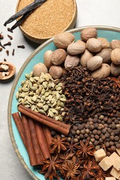 Different spices and nuts in bowls on light gray table, flat lay