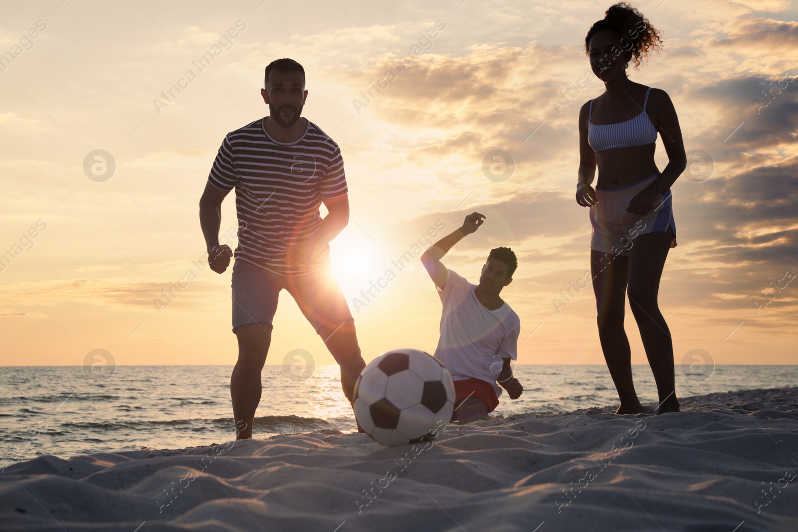 Photo of Friends playing football on beach at sunset