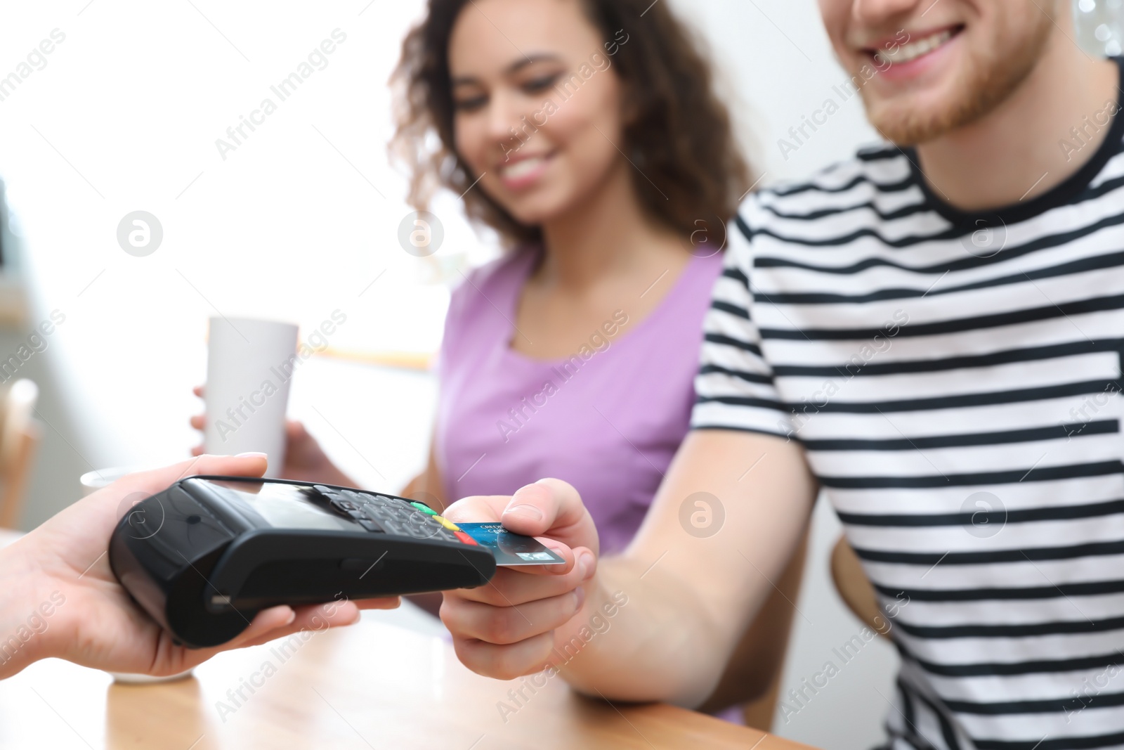 Photo of Clients using credit card machine for non cash payment in cafe, closeup