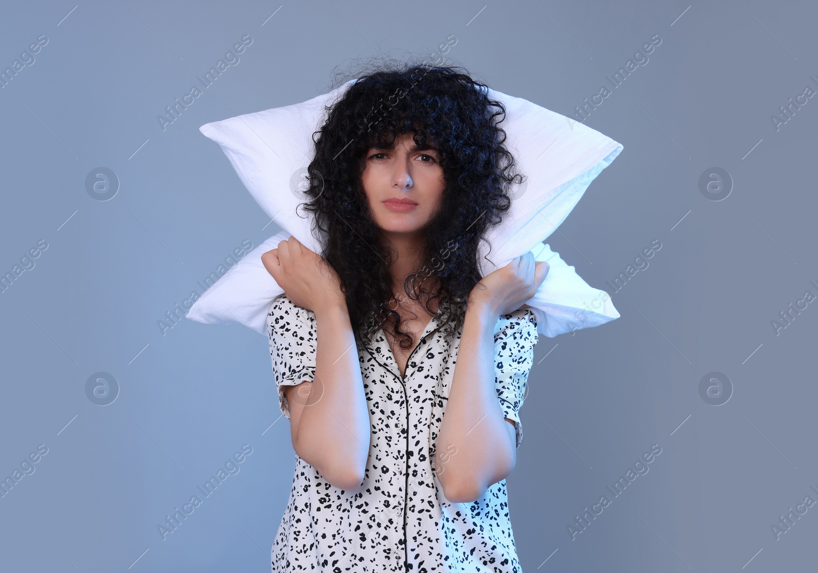 Photo of Tired young woman with pillow on light grey background. Insomnia problem