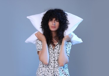 Photo of Tired young woman with pillow on light grey background. Insomnia problem