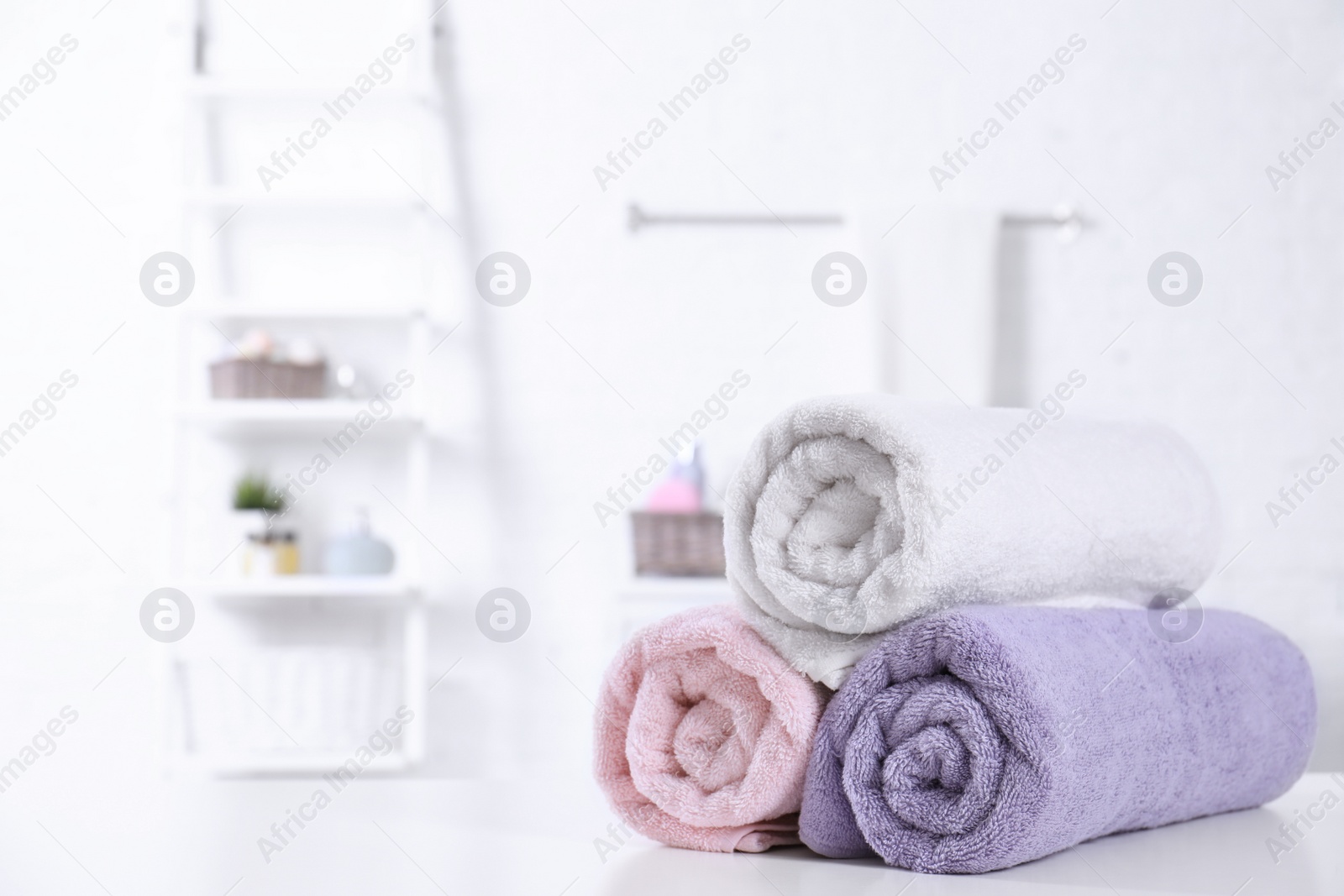 Photo of Rolled tidy towels on table in bathroom. Space for text