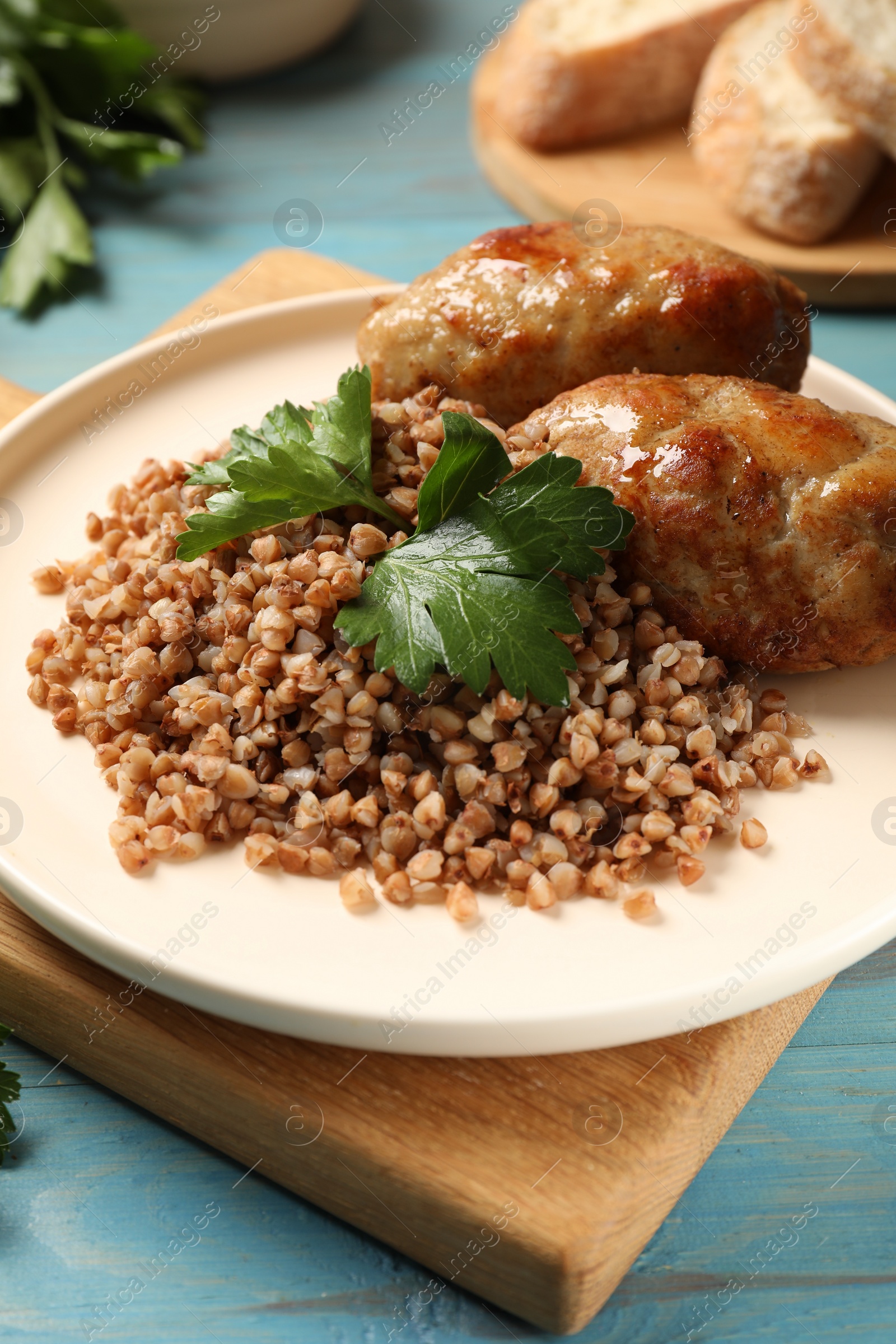 Photo of Tasty buckwheat with fresh parsley and cutlets on light blue wooden table, closeup