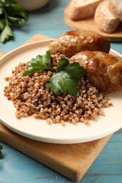 Photo of Tasty buckwheat with fresh parsley and cutlets on light blue wooden table, closeup