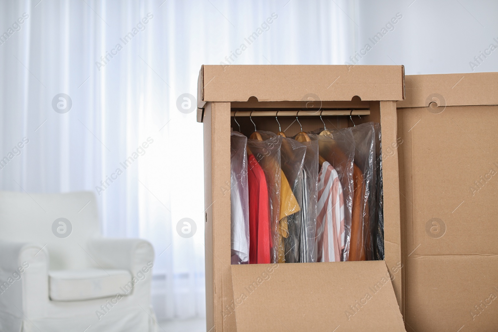 Photo of Wardrobe boxes with clothes in living room. Space for text