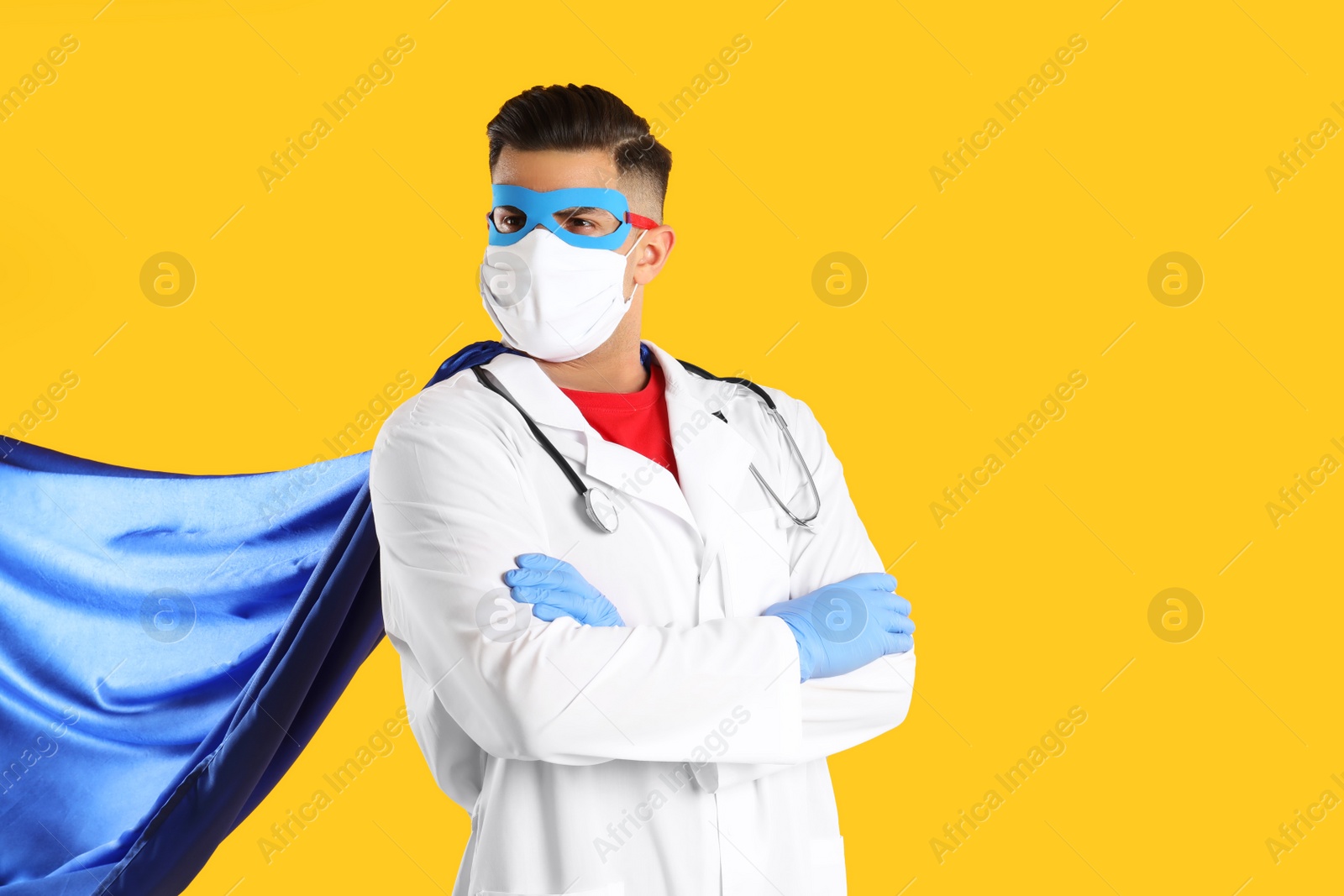 Photo of Doctor wearing face mask and cape on yellow background. Super hero power for medicine