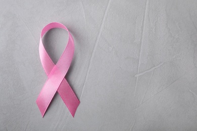 Pink ribbon on grey background, top view with space for text. Breast cancer awareness concept