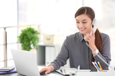 Young woman talking on phone at workplace