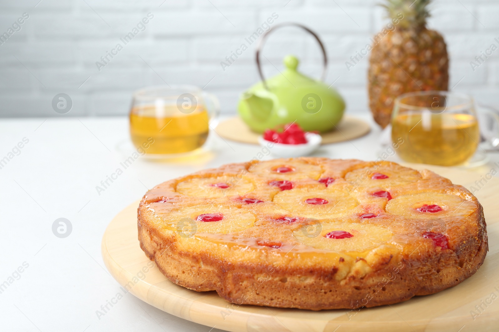 Photo of Tasty pineapple cake with cherries on white table. Space for text