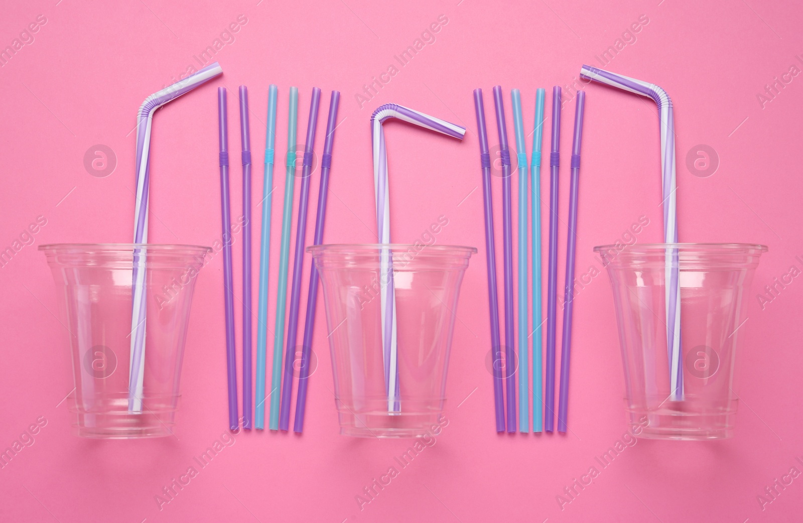 Photo of Plastic cups with straws on pink background, flat lay