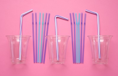 Plastic cups with straws on pink background, flat lay