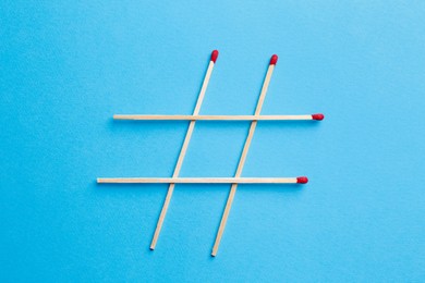 Photo of Hashtag symbol of matches on turquoise background, top view