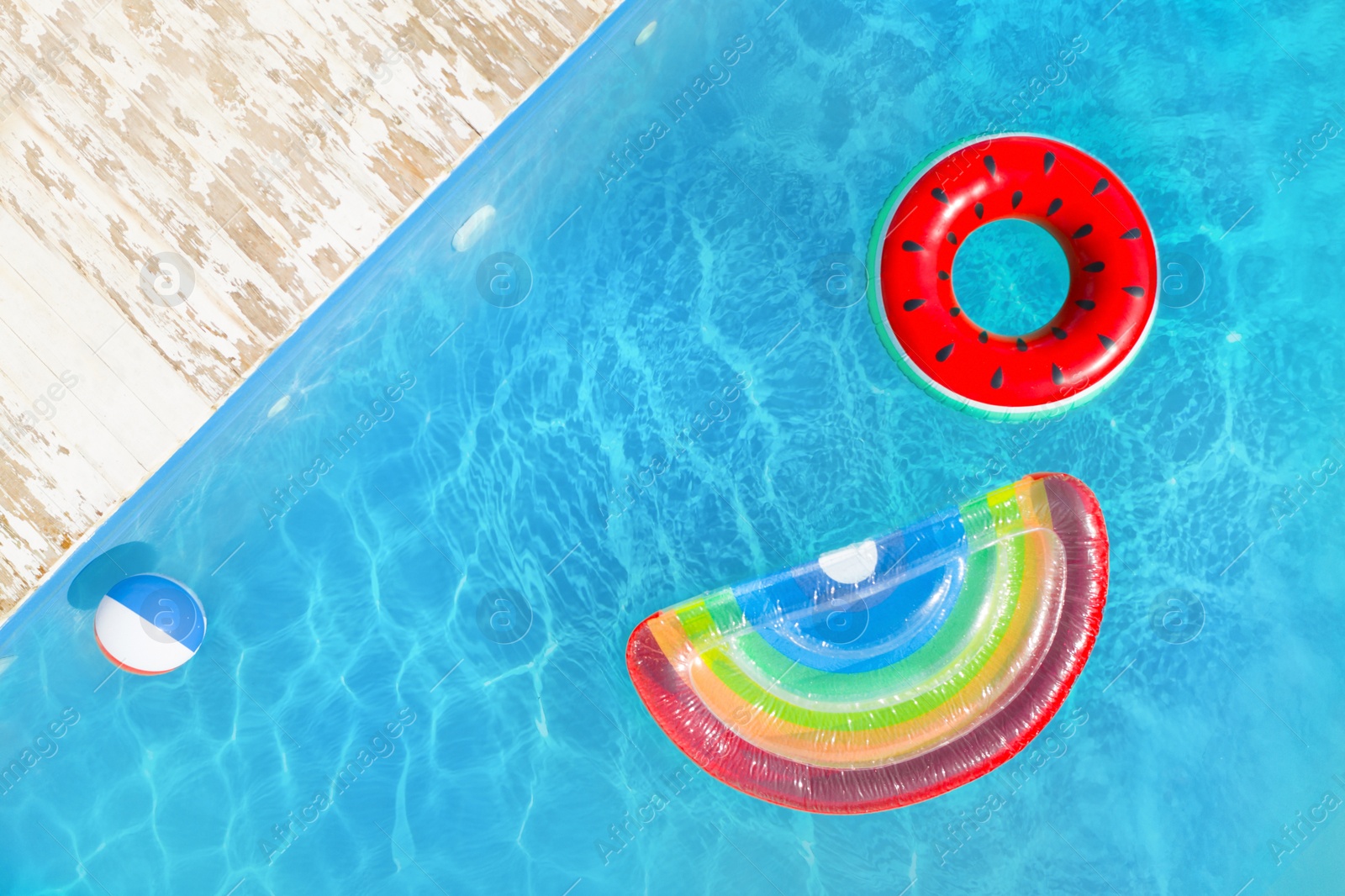Image of Swimming pool with inflatable ring, mattress and ball, top view