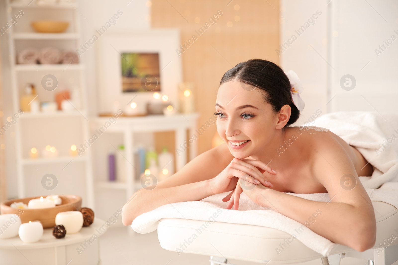 Photo of Beautiful young woman having massage with body scrub in spa salon