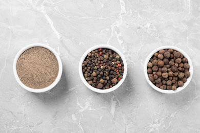 Photo of Ground pepper and corns on grey table, flat lay