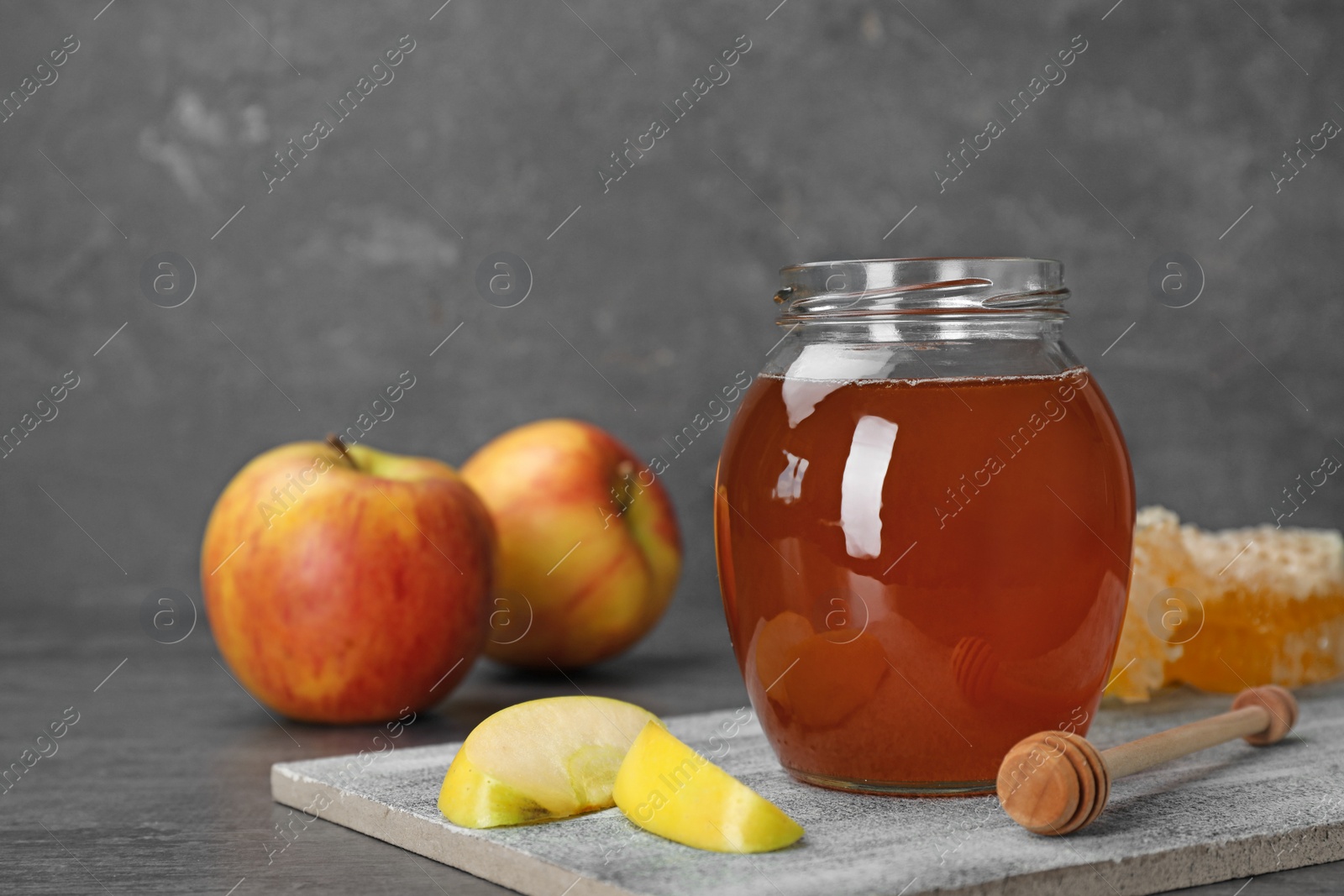 Photo of Jar of honey, apples and dipper on table