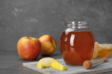 Jar of honey, apples and dipper on table