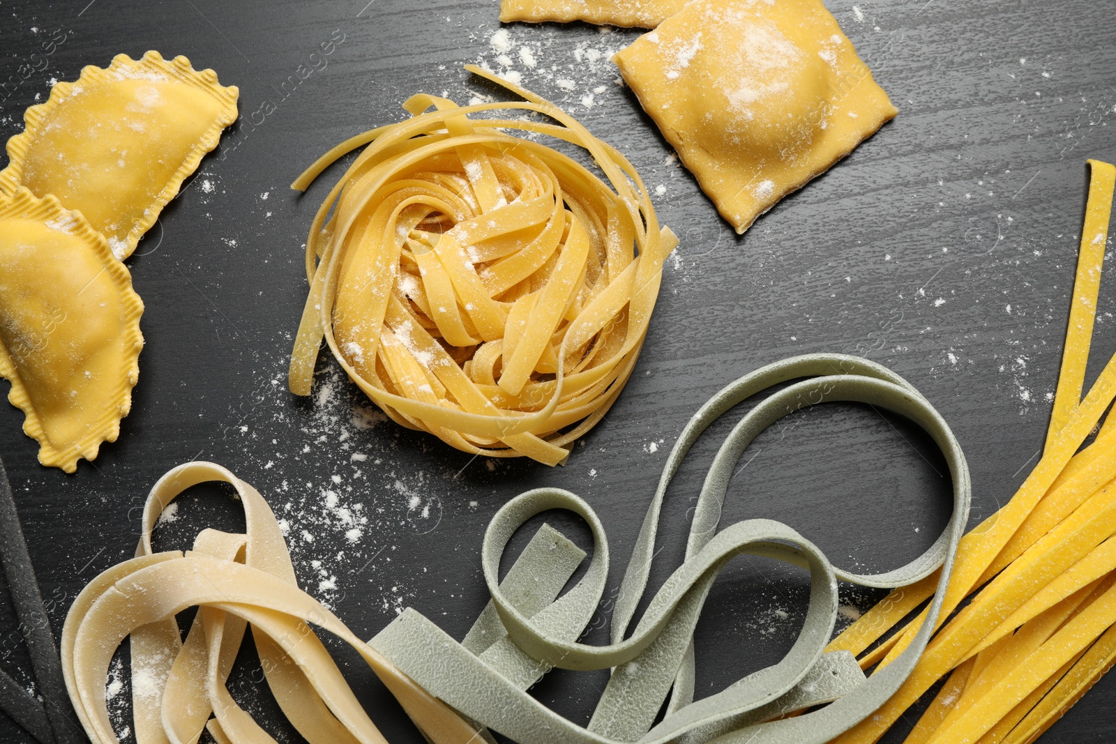 Photo of Flat lay composition with different types of pasta on black wooden table