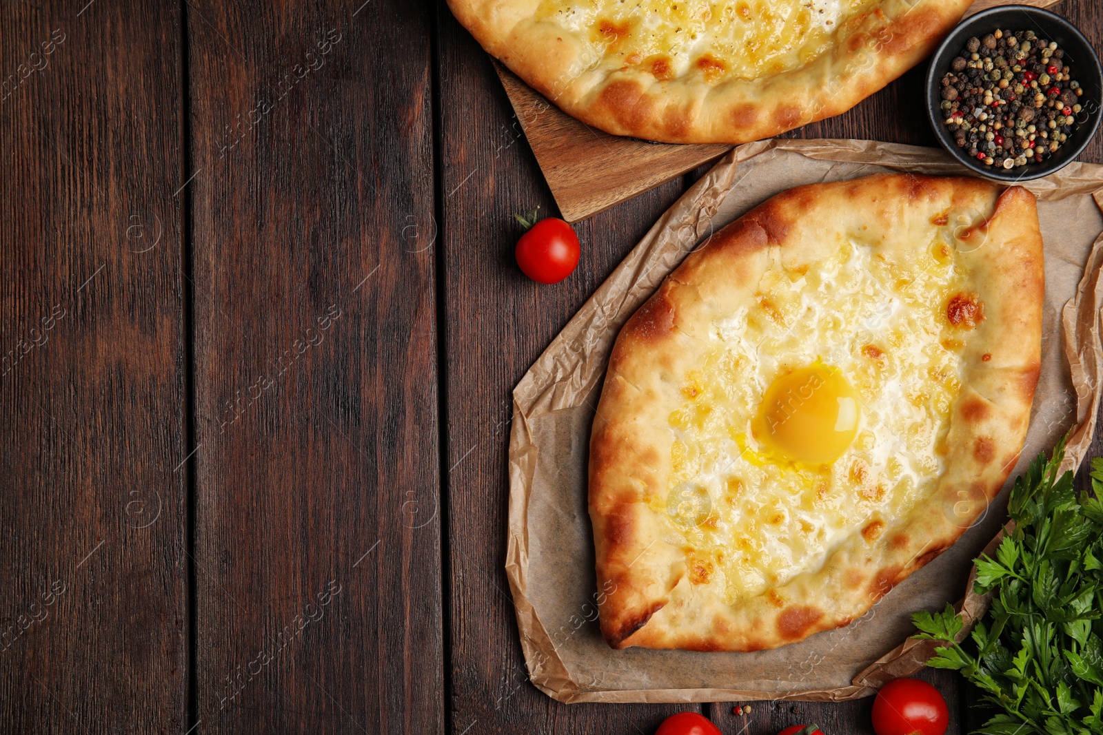 Photo of Fresh delicious Adjarian khachapuris served on wooden table, flat lay. Space for text