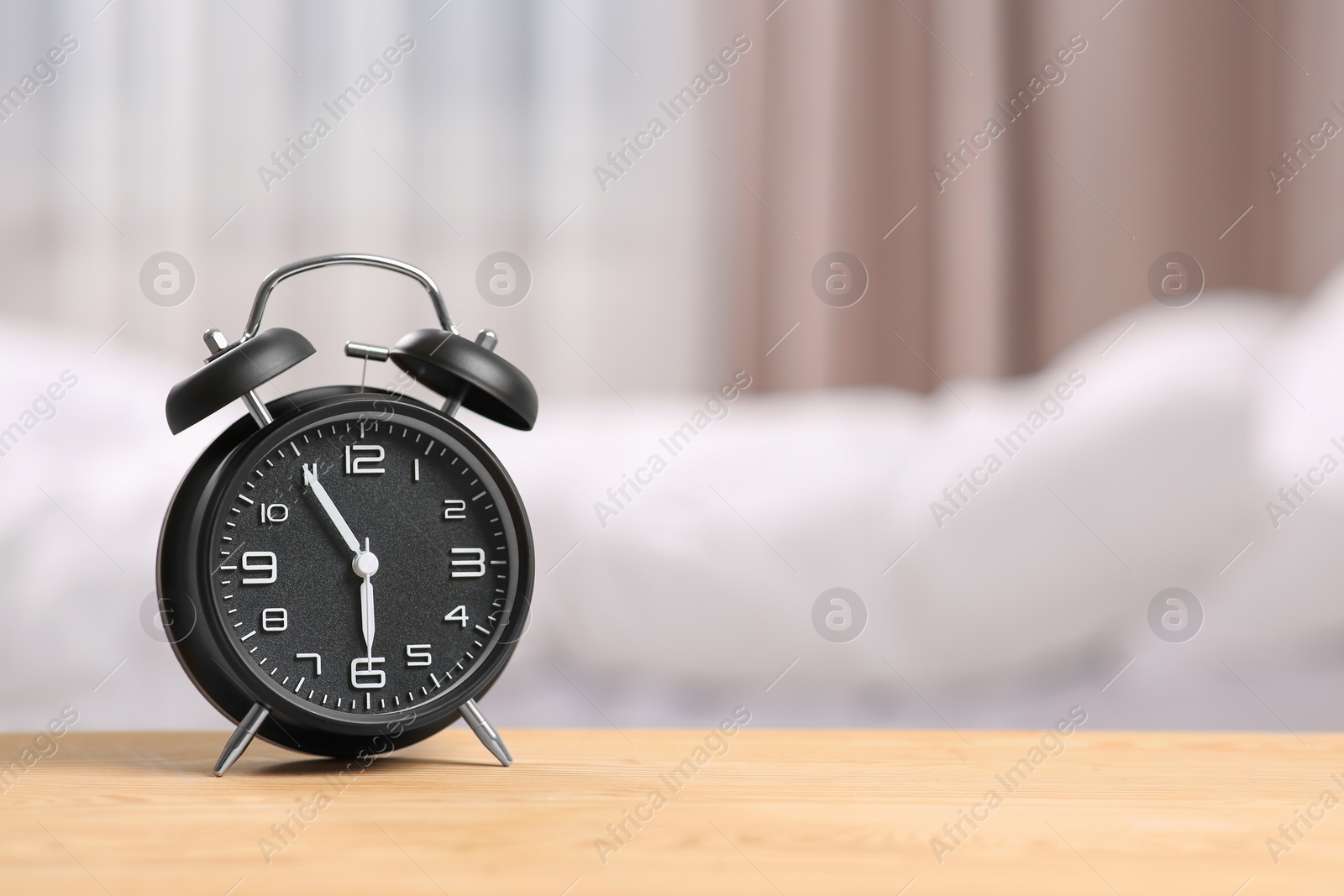 Photo of Black alarm clock on wooden table indoors. Space for text