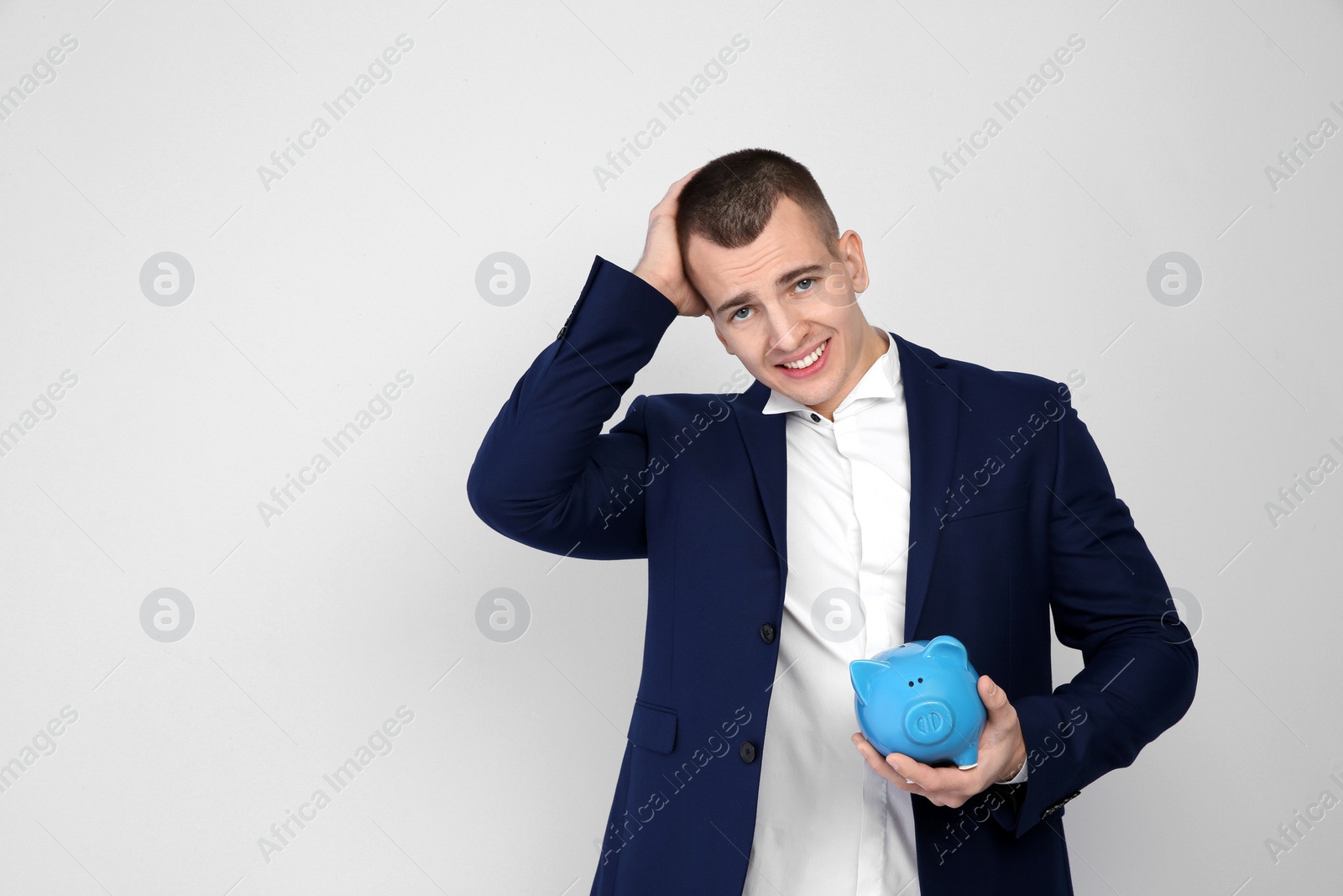 Photo of Young businessman with piggy bank on white background