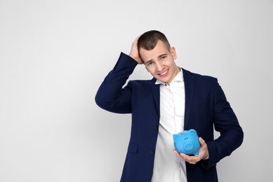 Young businessman with piggy bank on white background