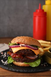 Photo of Tasty cheeseburger with patties, French fries and pickles on wooden table, closeup