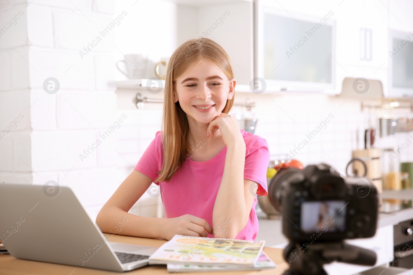 Photo of Cute teenage blogger with laptop recording video at table