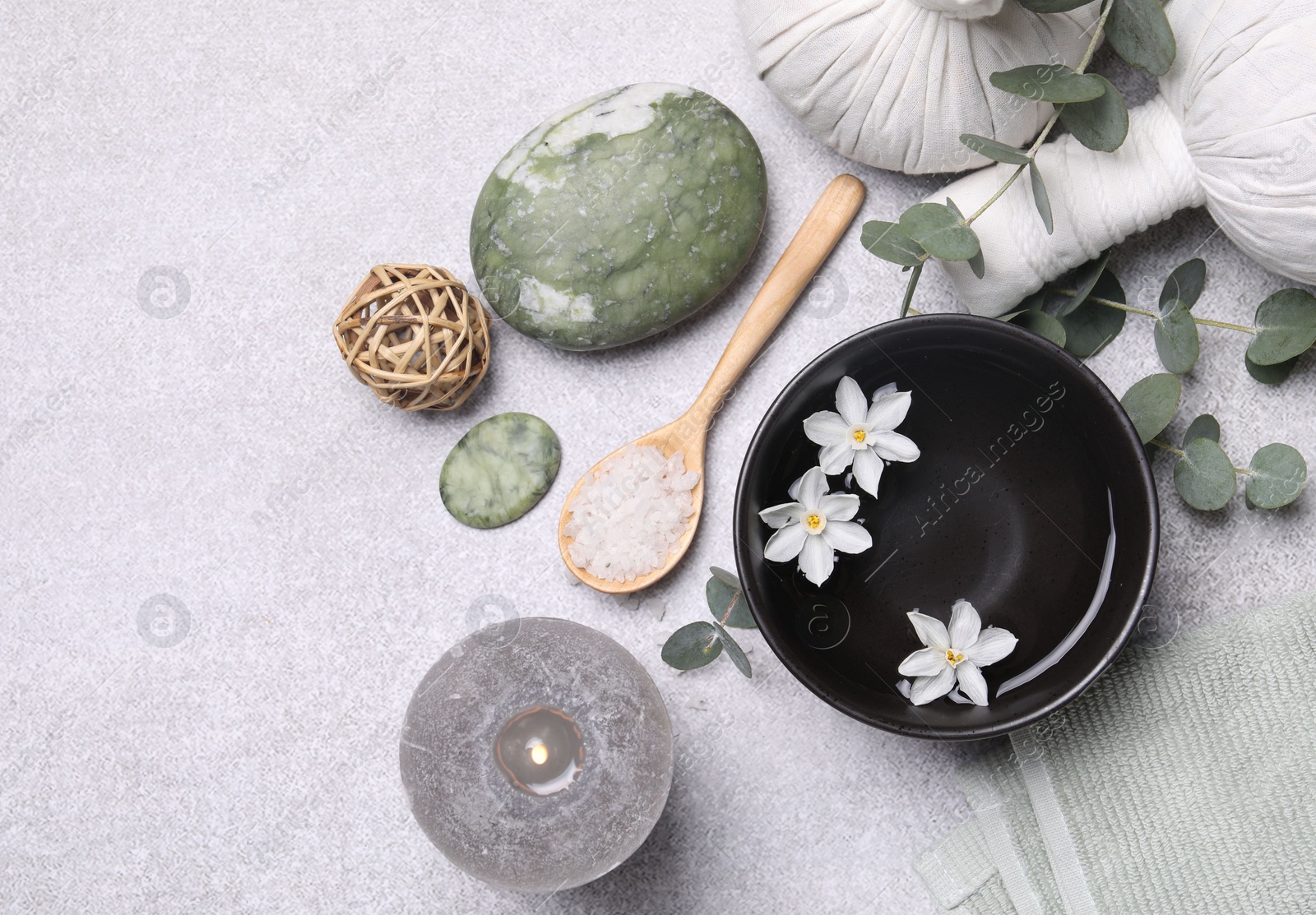 Photo of Flat lay composition with herbal massage bags, spa products and flowers on light grey table