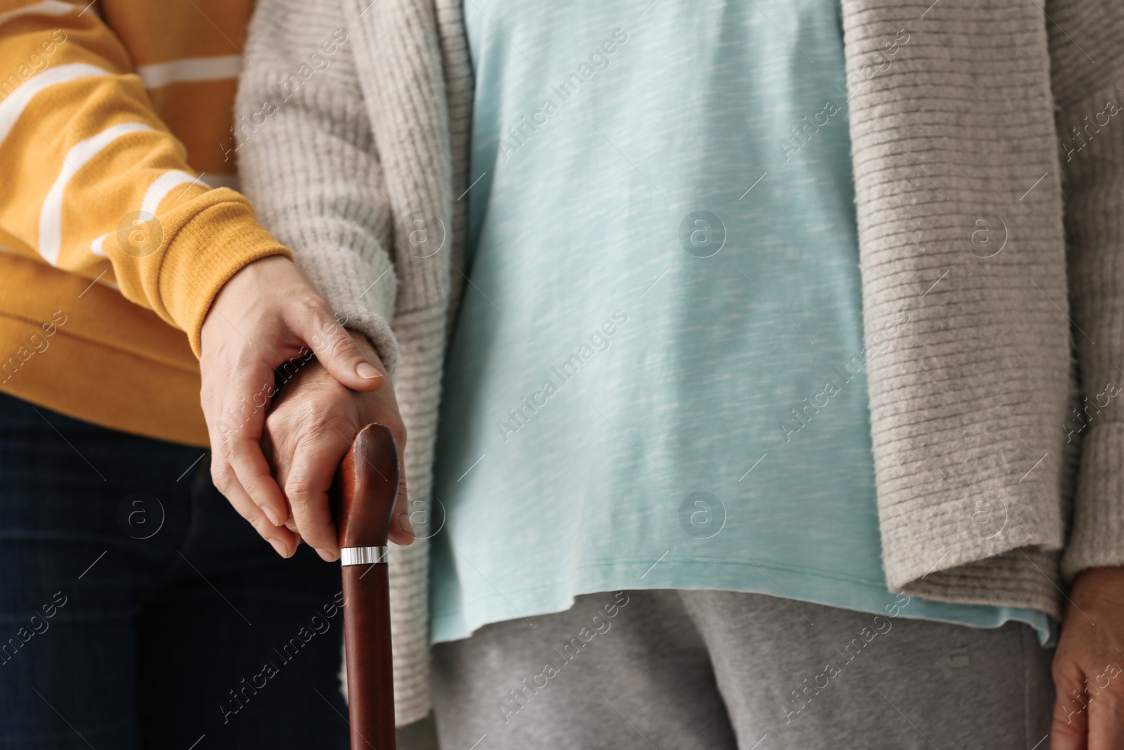 Photo of Elderly woman with walking cane and female caregiver, closeup view