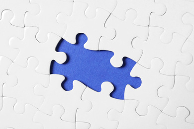 Photo of Blank white puzzle with missing pieces on blue background, top view