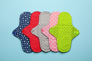 Photo of Many reusable cloth menstrual pads on light blue background, flat lay
