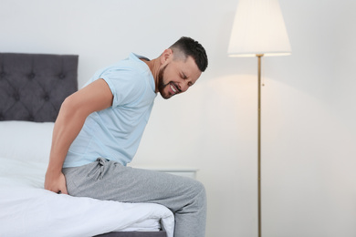 Photo of Man suffering from hemorrhoid on bed at home