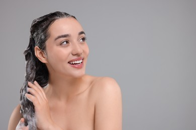 Photo of Beautiful happy woman washing hair on grey background. Space for text