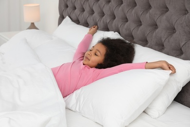 Cute little African-American girl sleeping in bed