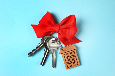 Photo of House keys with trinket and bow on color background, top view