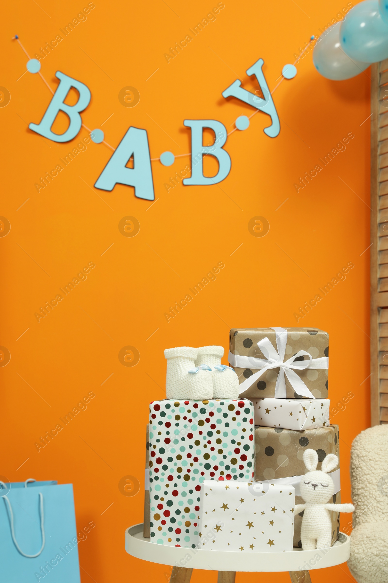 Photo of Baby shower party. Festive decor, booties, toy and gift boxes indoors, space for text