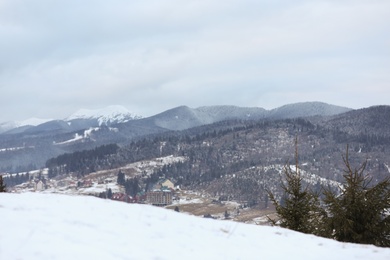 Photo of Winter landscape with mountain village near conifer forest