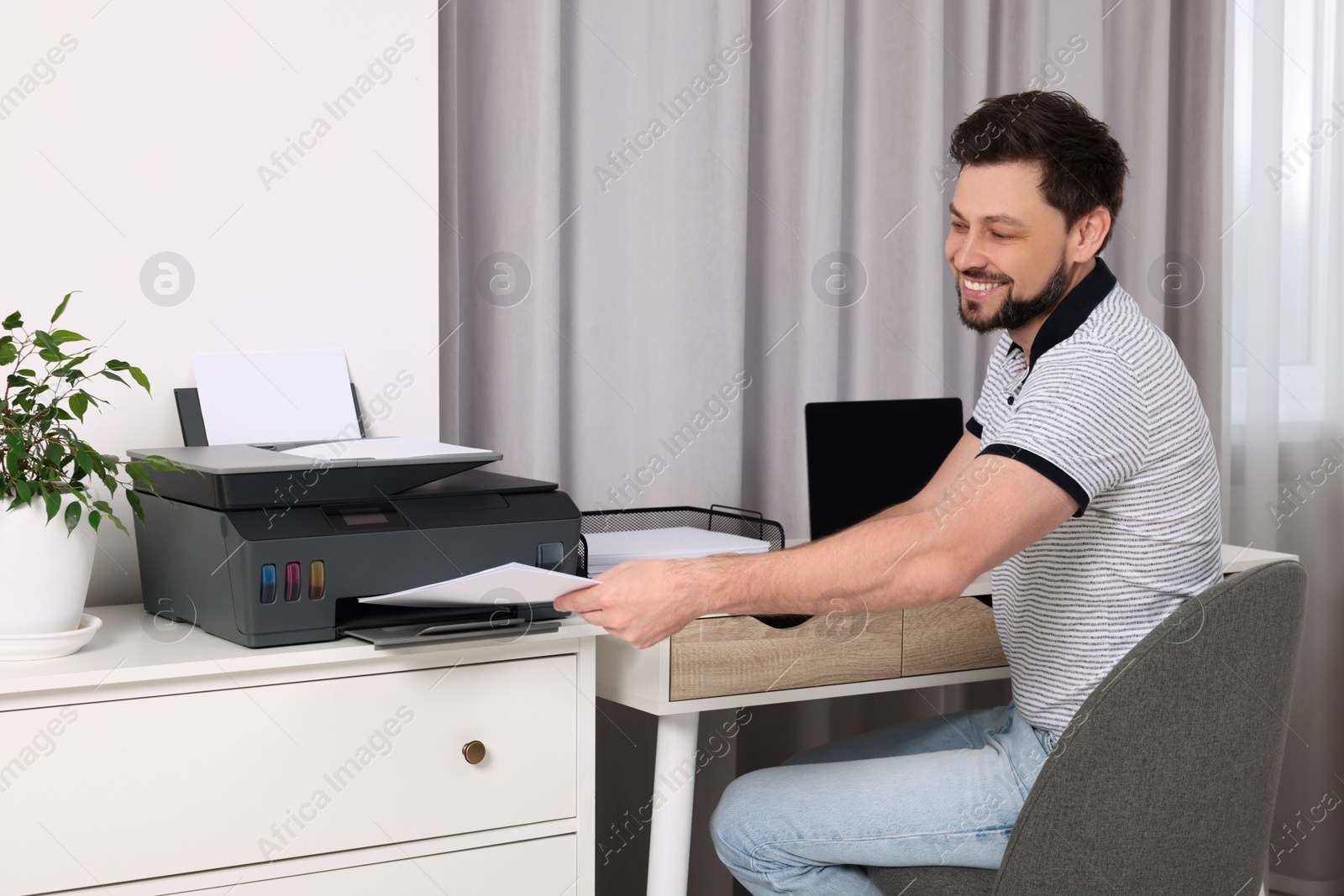 Photo of Man using modern printer at workplace indoors