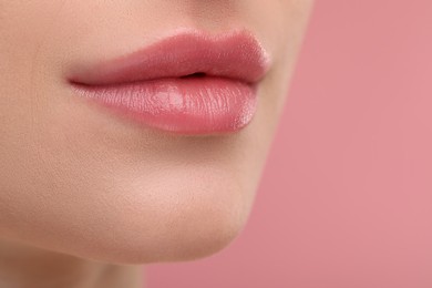 Photo of Young woman with beautiful full lips on pink background, closeup