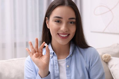 Photo of Beautiful young woman showing pill at home