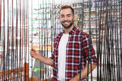 Man choosing fishing rod in sports shop