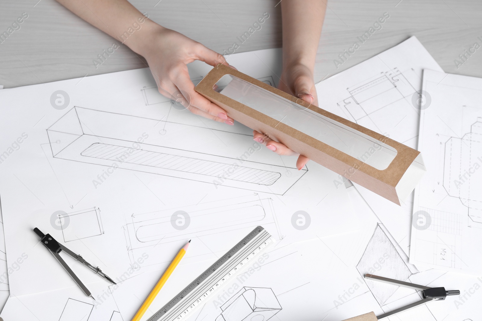 Photo of Woman creating packaging design at light wooden table, top view