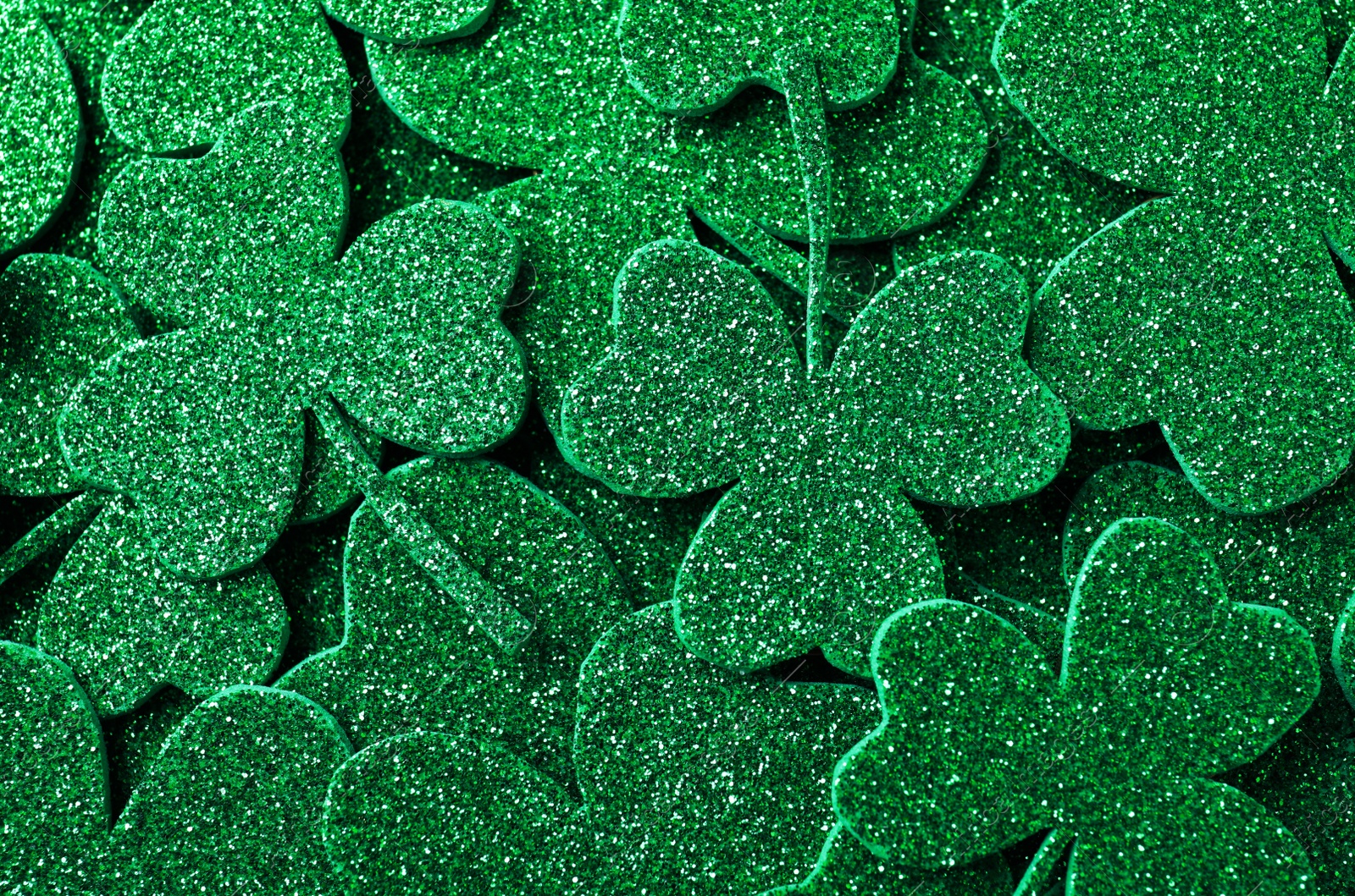 Photo of Glitter green clover leaves as background, top view. St. Patrick's Day celebration