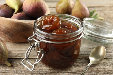 Jar of tasty sweet fig jam on wooden table