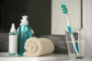 Photo of Light blue toothbrush in glass holder on table, space for text